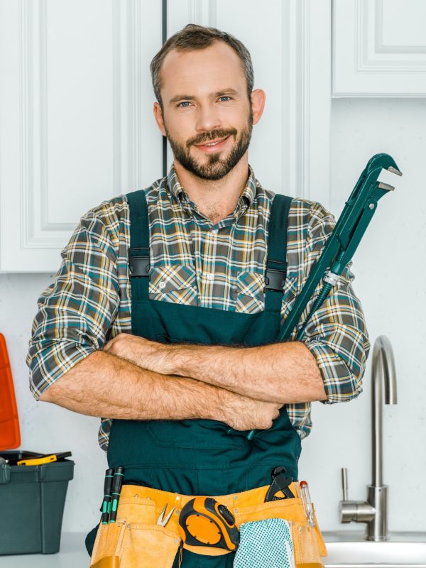 handsome-plumber-holding-monkey-wrench-and-looking-at-camera-in-kitchen.jpg